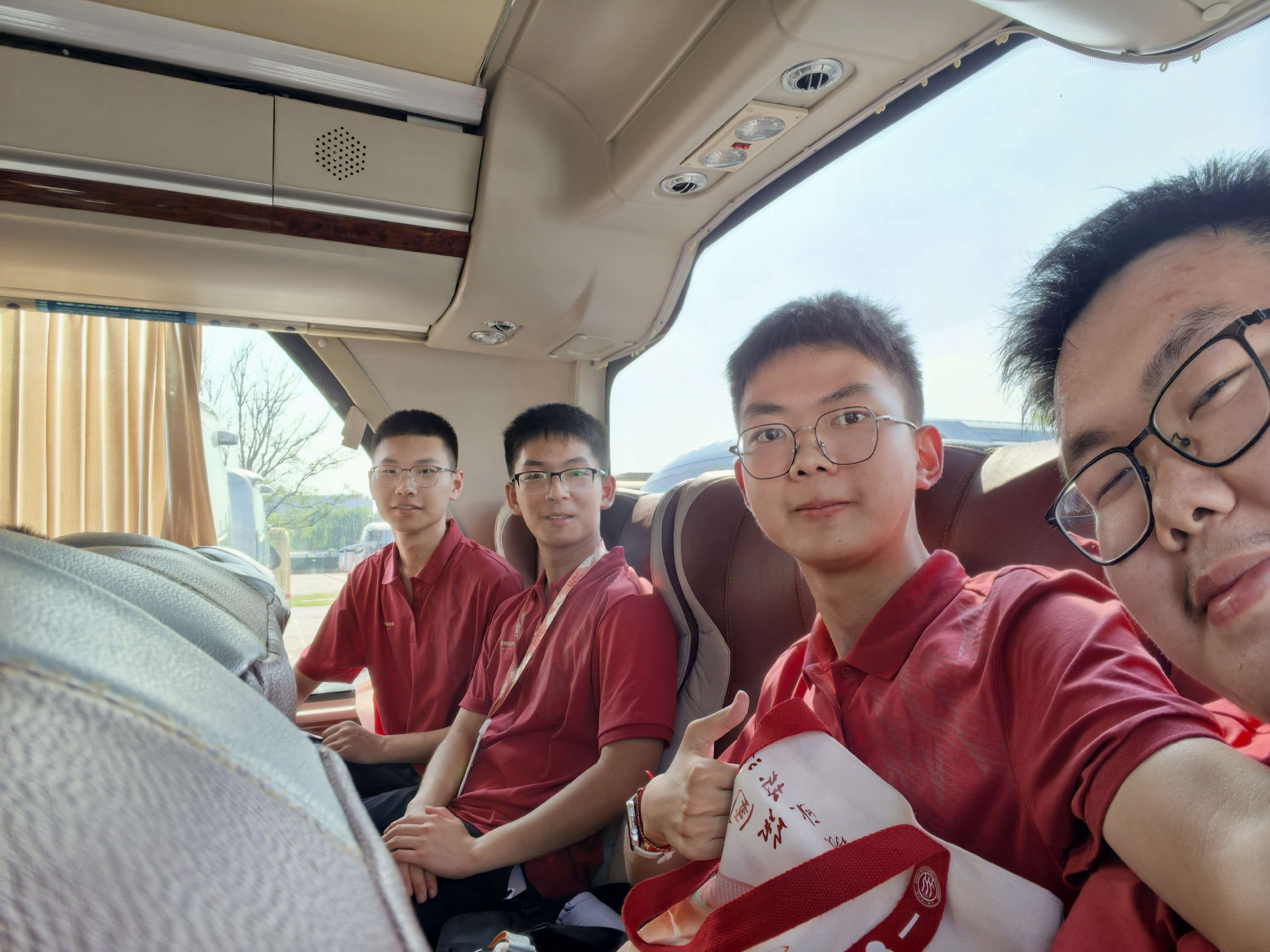 同学们穿着红色上衣坐在大巴车内